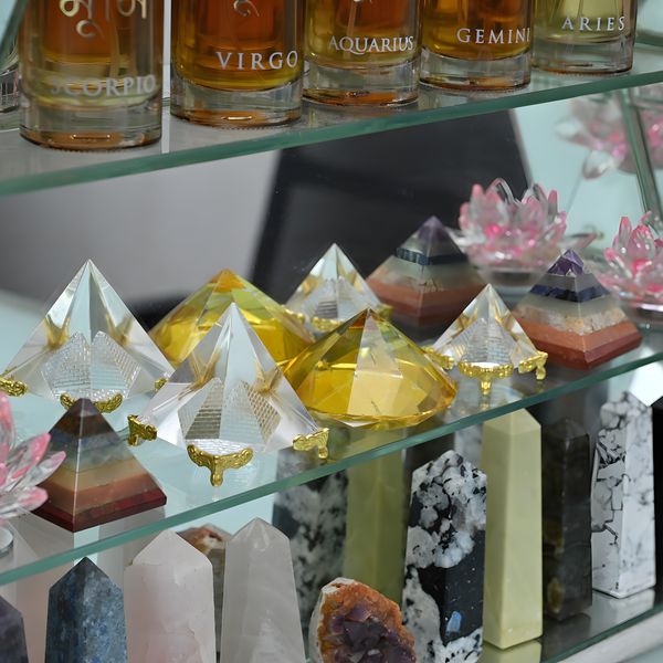 Bottles of aroma oil labelled with zodiac signs beside crystal pyramids and crystal lotuses
