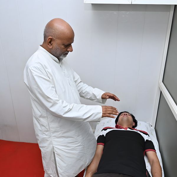 Sanjay Shrivastava holding his hands just above a client’s head during Reiki