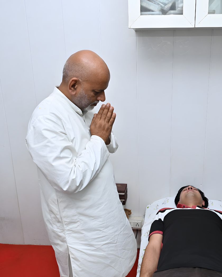 Sanjay Shrivastava with folded hands in prayer beside a client during a healing session